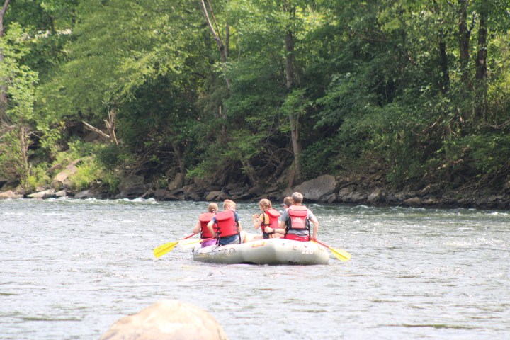Group of people rafting on a river surrounded by trees.