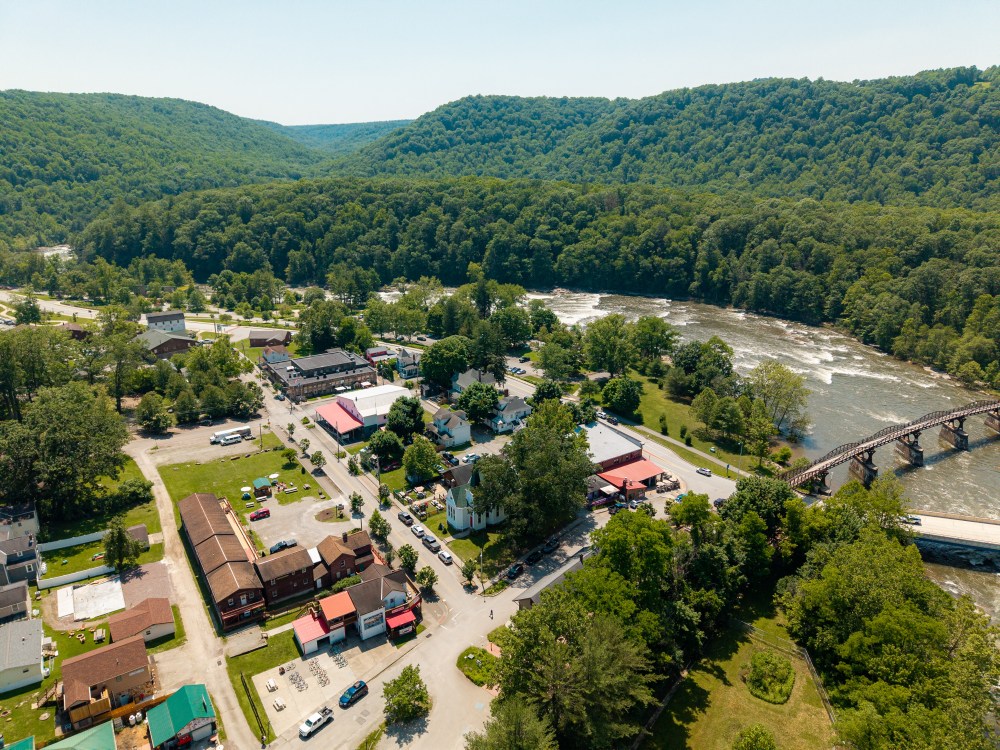 Aerial view of a small town with river and forested hills.