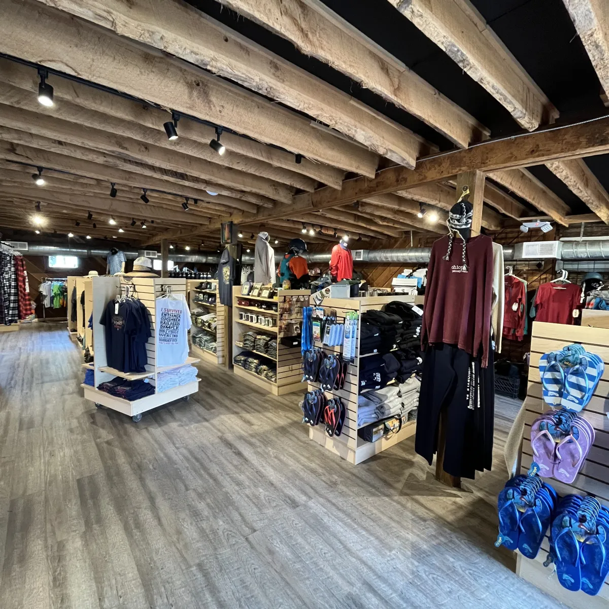 Clothing store interior with wooden beams and various apparel displays.