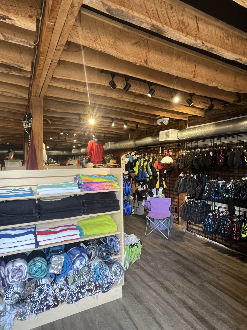 Clothing and accessories displayed in a rustic store with wooden beams.