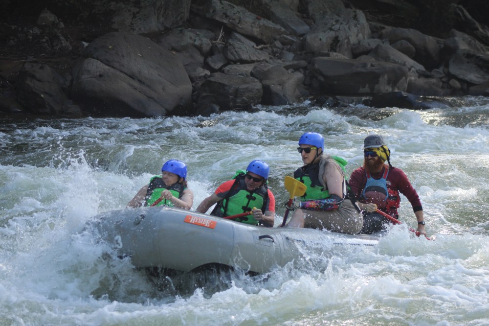 Group of people white water rafting on a river.